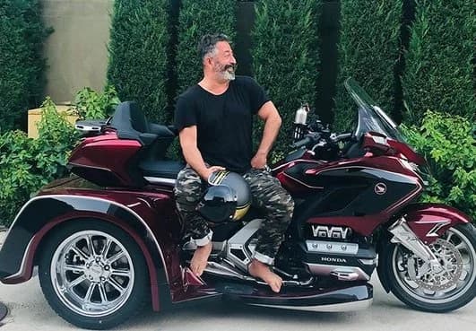 Cem Yılmaz, bordo Honda Gold Wing trike motosikletinin üzerinde